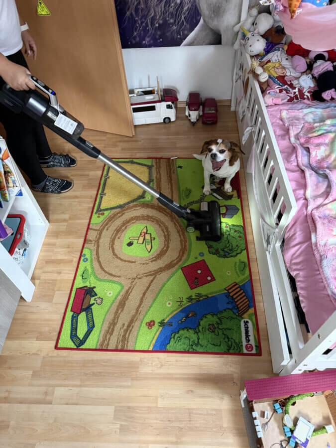 Der Akkustaubsauger im Einsatz auf einem Teppich im Kinderzimmer.